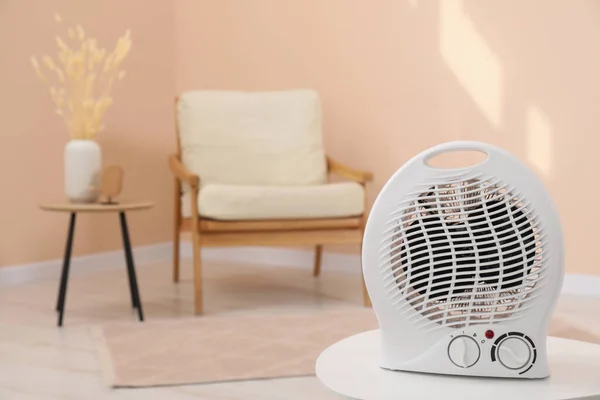 Compact electric fan heater on white table indoors. Space for text