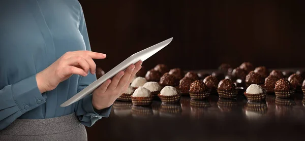 Production line of chocolate candies. Woman working with tablet, closeup. Banner design