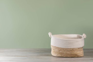 Empty wicker laundry basket near light green wall. Space for text