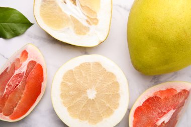Different sorts of tasty pomelo fruits on white marble table, flat lay