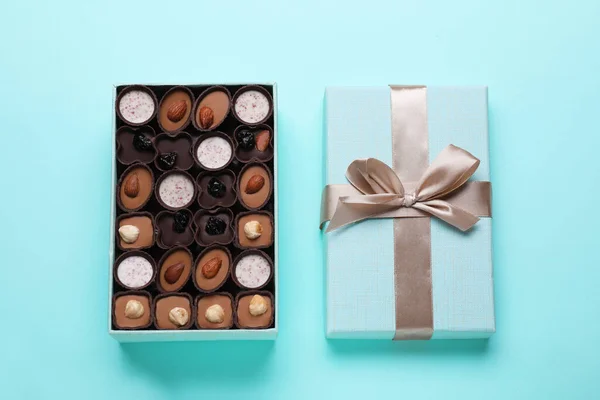 Open box of delicious chocolate candies on light blue background, flat lay