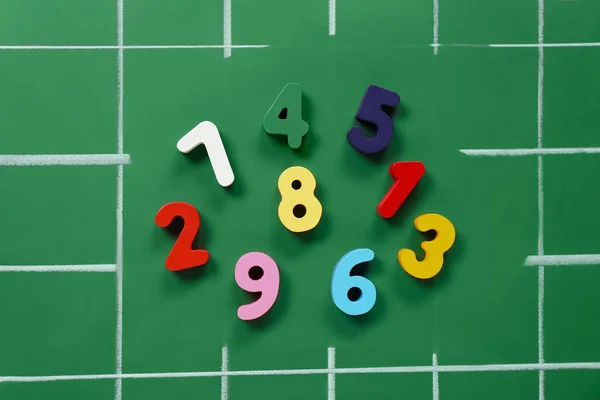 Many colorful numbers on green chalkboard, flat lay