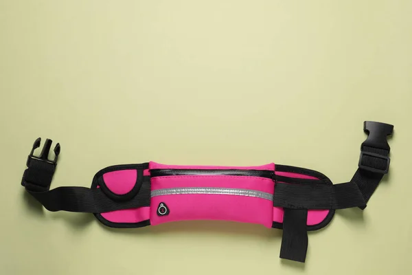 Stylish pink waist bag on pale green background, top view. Space for text