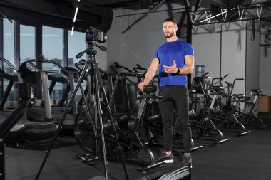 Man recording online training on camera at gym. Fitness coach