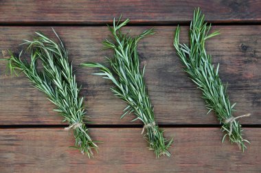 Bunches of fresh rosemary on wooden table, flat lay. Aromatic herb