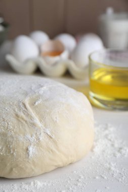 Fresh yeast dough with flour on white wooden table, closeup
