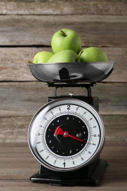 Kitchen scale with green apples on wooden table