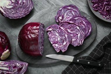 Taze olgun kırmızı lahana dilimleri ve bıçak gri masada, düz yatıyordu.