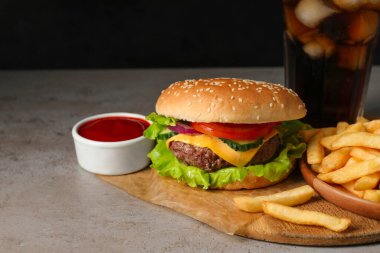 Delicious burger, soda drink and french fries served on grey table. Space for text