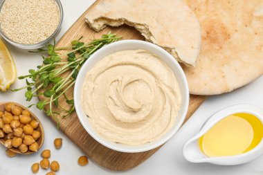 Delicious hummus and different ingredients on white marble table, flat lay