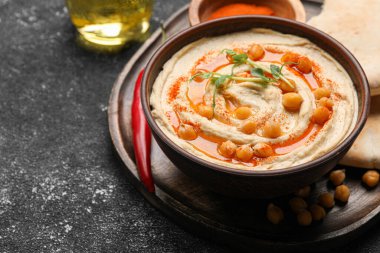 Delicious hummus with chickpeas and different ingredients on grey textured table. Space for text