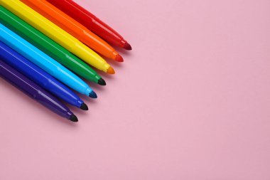 Açık pembe arka planda, düz zeminde birçok farklı renkli işaret var. Metin için boşluk