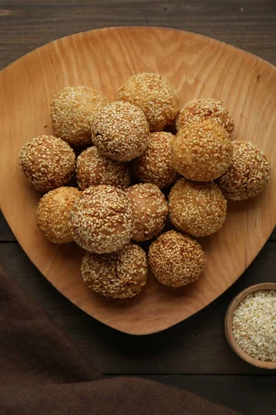 Delicious sesame balls on wooden table, flat lay