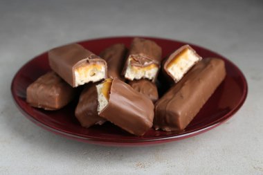 Tasty chocolate bars with caramel on light grey textured table