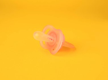 One new baby pacifier on orange background