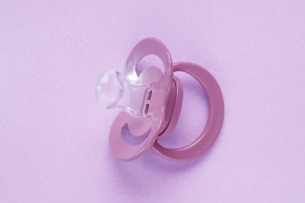 One new baby pacifier on pink background, top view