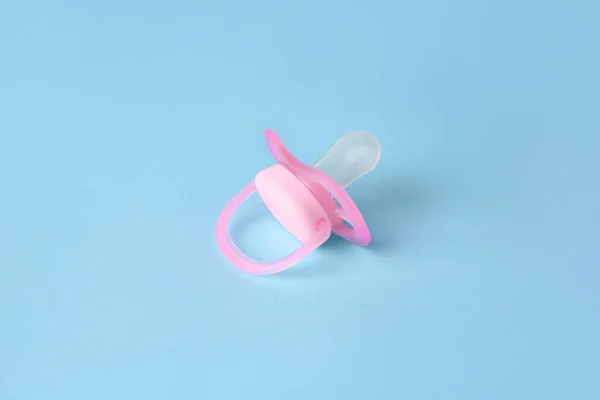 One new baby pacifier on light blue background