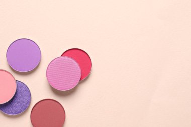 Different beautiful eye shadows on beige background, flat lay. Space for text