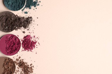 Different crushed eye shadows on beige background, flat lay. Space for text