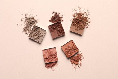 Different crushed eye shadows on beige background, flat lay