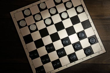 Checkerboard with game pieces on wooden table, top view