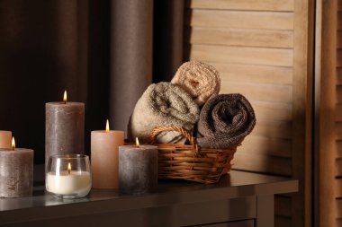 Spa composition with burning candles and rolled towels on table in wellness center