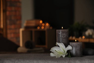 Spa composition with burning candles, lily flower and stone on massage table in wellness center, space for text