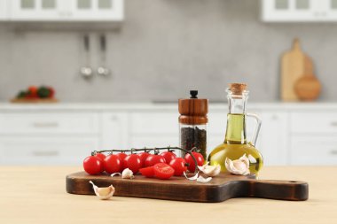 Fresh cherry tomatoes, oil, garlic and peppercorns on wooden table in kitchen