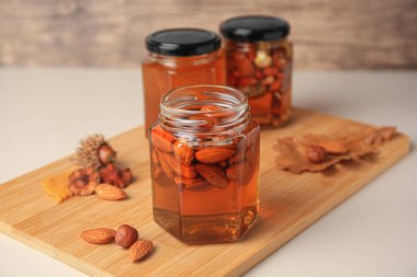 Jars with different nuts and honey on white table