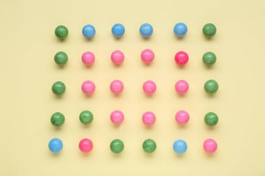 Many bright chewy gumballs on beige background, flat lay