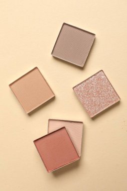 Different beautiful eye shadows on beige background, flat lay