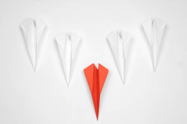 Handmade colorful paper planes on white table, flat lay. Leadership concept