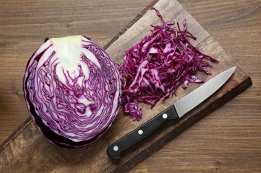 Delicious fresh shredded red cabbage and knife on wooden table, flat lay