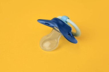 One blue baby pacifier on orange background