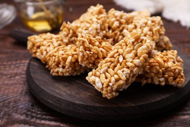 Board with puffed rice bars (kozinaki) on wooden table, closeup