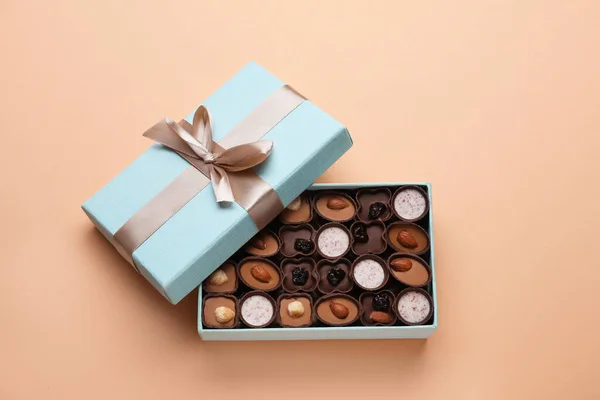 Open box of delicious chocolate candies on beige background, flat lay