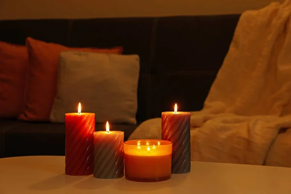 Burning candles on white table indoors. Cosy atmosphere
