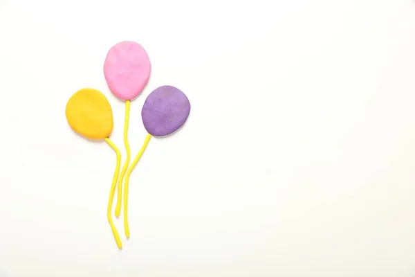 Beautiful balloons made of plasticine on white background, top view