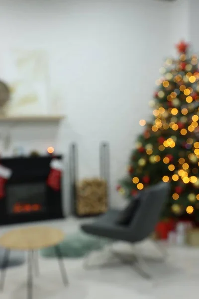 Beautiful Christmas tree near fireplace in room, blurred view