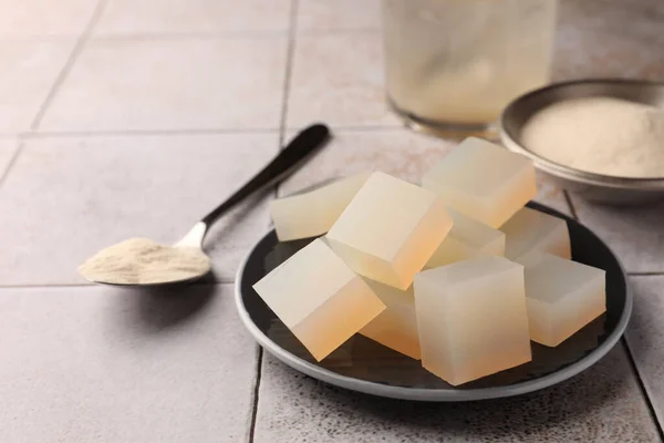 Agar-agar jelly cubes and powder on tiled surface, closeup