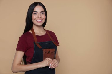 Portrait of happy hairdresser on beige background, space for text