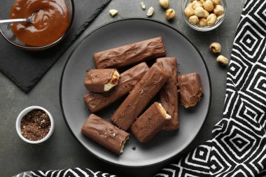 Tasty chocolate bars with caramel and nuts on grey table, flat lay