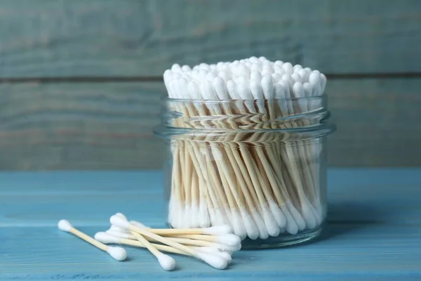 Many cotton buds on light blue wooden table