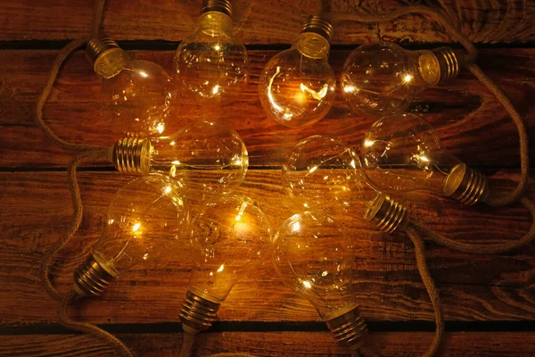 String lights with lamp bulbs on wooden table, top view