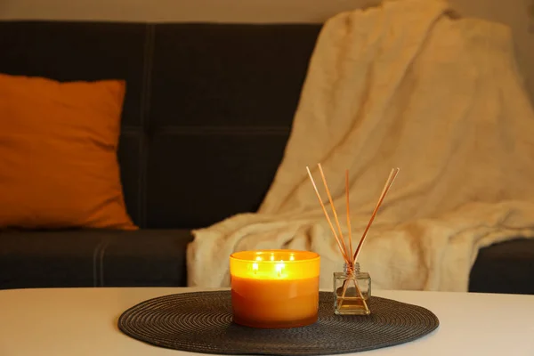 Beautiful candle and reed air freshener on white table indoors. Cosy atmosphere