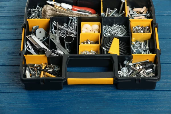 Plastic box with different furniture fittings and tools on blue wooden table, above view