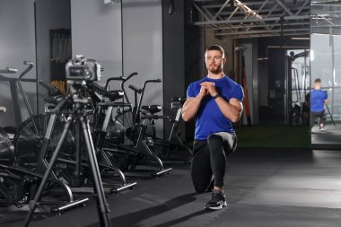 Man recording workout on camera at gym. Online fitness trainer