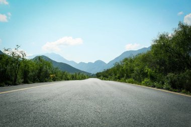 Picturesque view of big mountains and bushes near road under bright sky