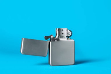 Gray metallic cigarette lighter on light blue background