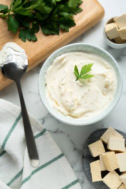 Delicious tofu cheese with parsley and spoon on white marble table, flat lay